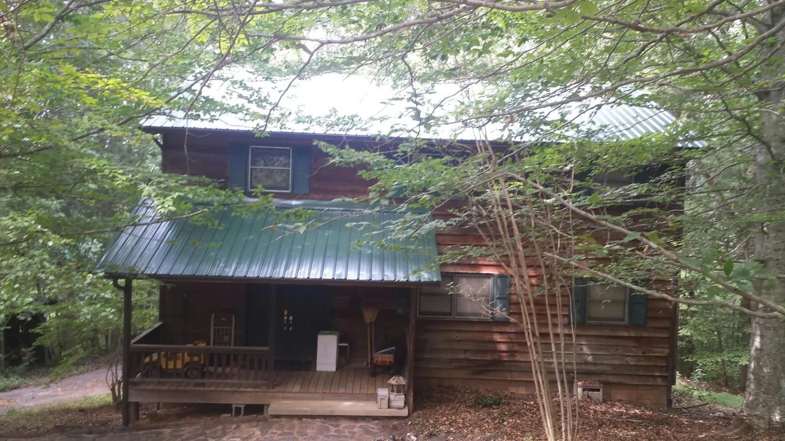 Green metal roof and covered porch on a log cabin in Mc Veytown