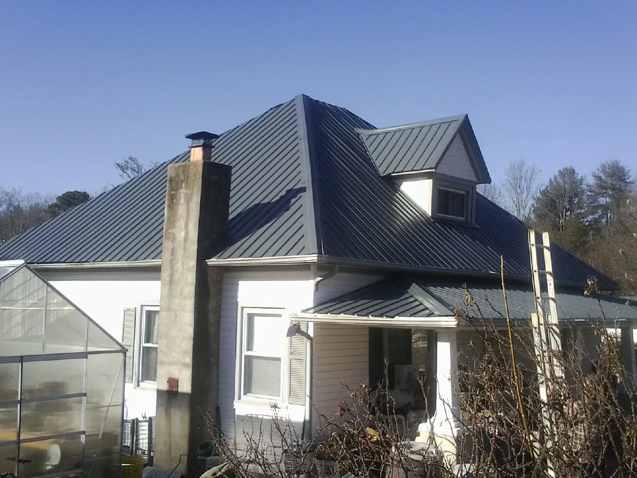 Dark blue standing seam metal roof on a white farmhouse with dormer — Slate & Tile Roof Repair by Roofing Brothers in Mc Veytown