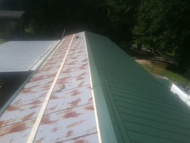 Old rusted panels beside newly installed green metal roofing — Wind Damage Roof Repair by Roofing Brothers in Mc Veytown