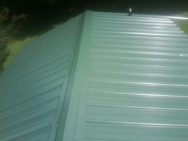 New green metal panels meeting at the ridge of a roof — Flat Roof Repair work by our crew in Mc Veytown