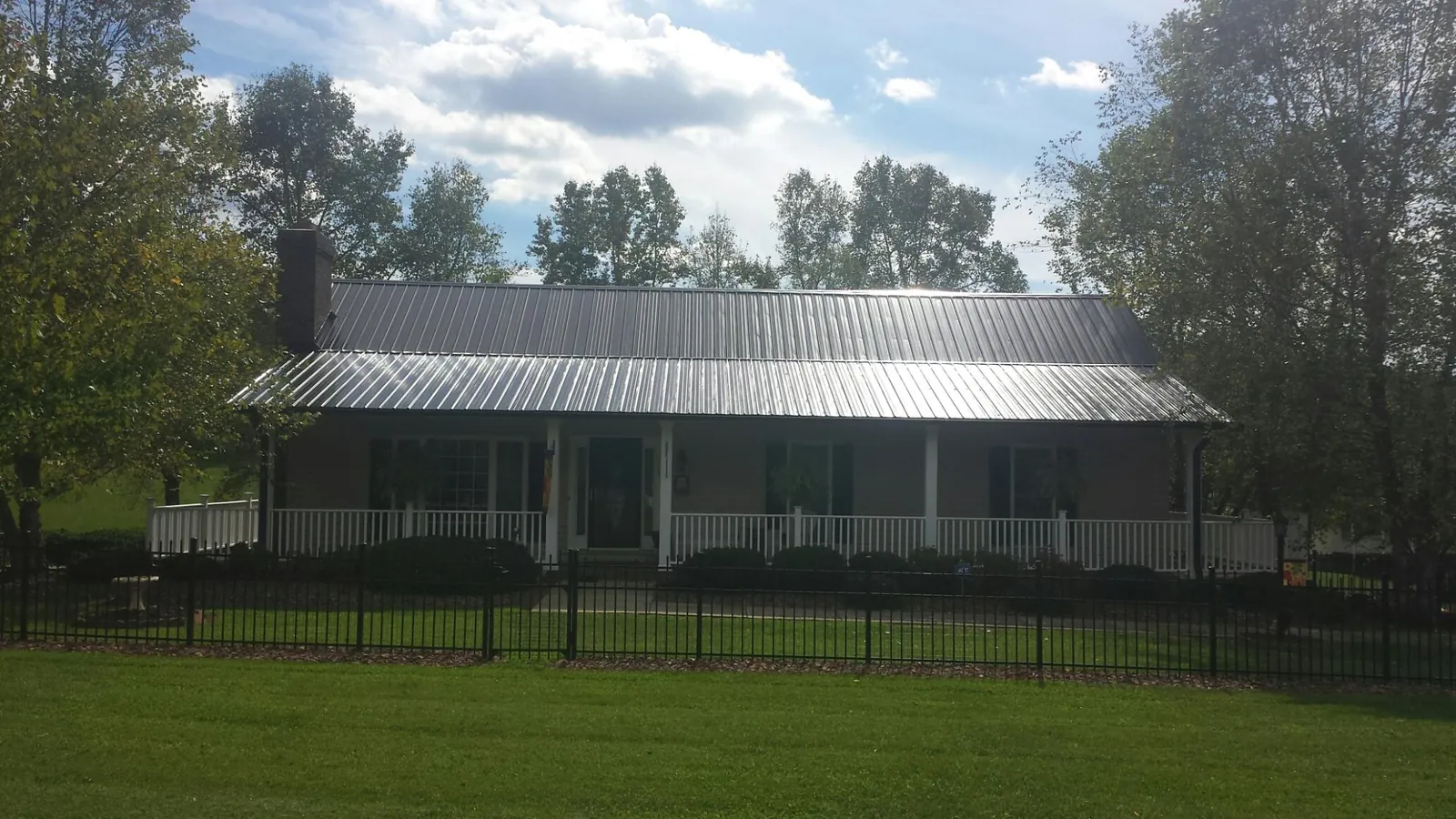 Gray metal roof on a brick ranch with a full width front porch — Gutter Guard Installation work by our crew in Mc Veytown