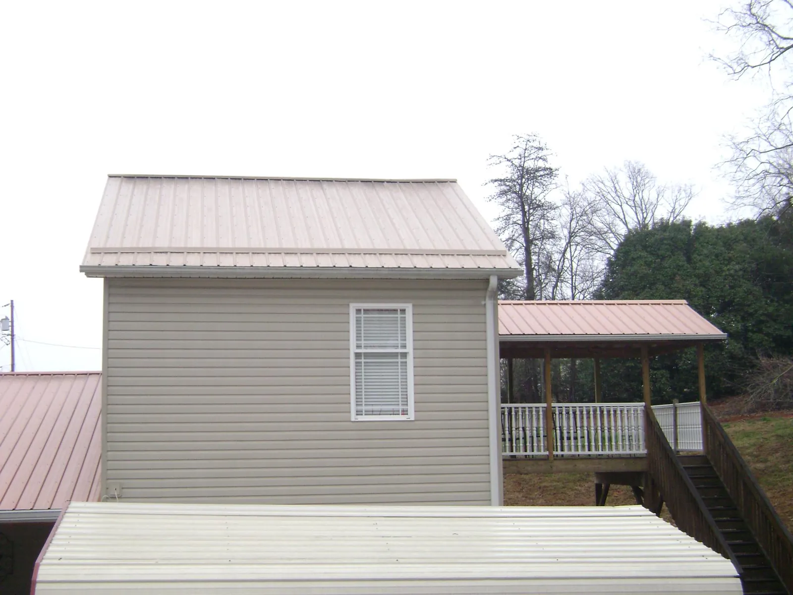 Tan metal roofs on a two story addition and attached porch, from a Roof Replacement job in Mc Veytown