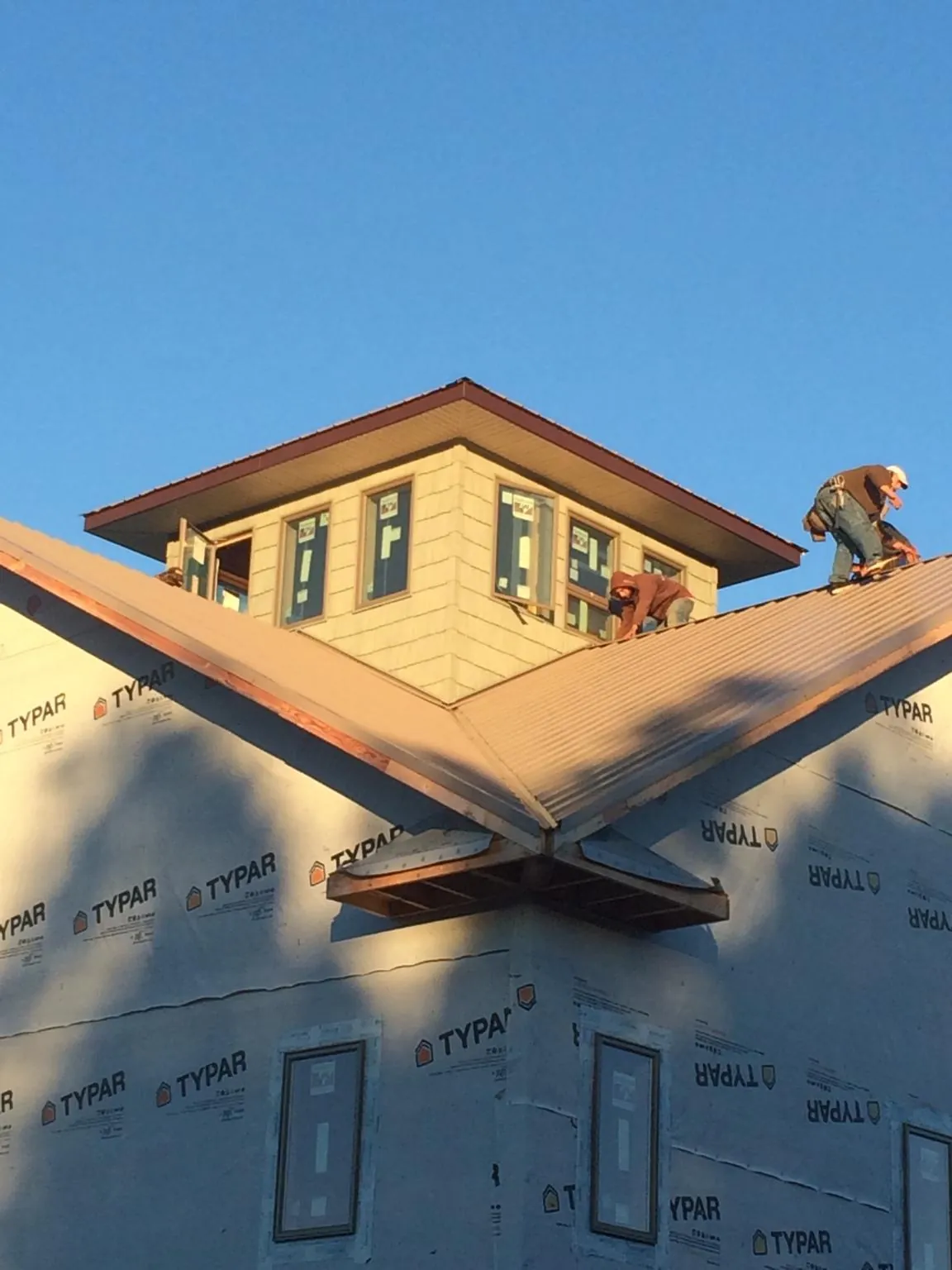 Roofers working around a rooftop cupola on a new metal roof at sunset — Roof Waterproofing in Mc Veytown by Roofing Brothers